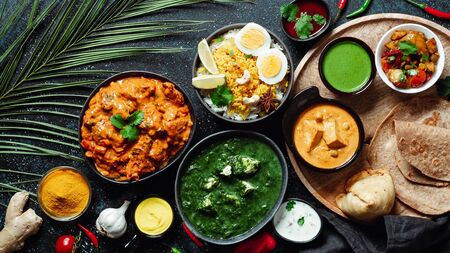 Indian cuisine dishes: tikka masala, paneer, samosa, chapati, chutney, spices. Indian food on dark background. Assortment indian meal top view or flat lay. Copy space for text.の写真素材