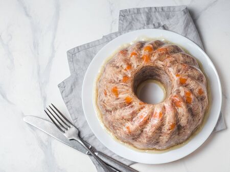 Homemade delicious jelly meat on white marble table. Perfect jellied meat, aspic, galantine with...