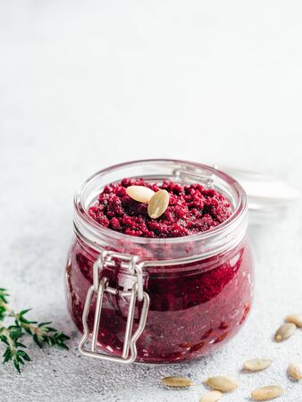 Beetroot pesto or hummus. Homemade beet pesto sauce in glass jar and fresh thyme on dark black background. Copy space for text. Ideas and recipes for healthy vegetarian detox diet foodの写真素材