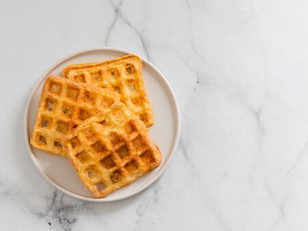 Delicious savory keto waffles. Two ingredients chaffles on plate over white marble background. Eggs and parmesan cheese low carb waffles. Top view or flat lay. Copy space right for text or design.の写真素材