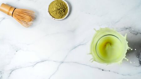 Homemade iced matcha latte with splashes over white marble background. Top view or flat lay. Copy space for text or designの写真素材
