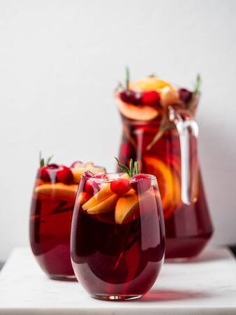 Winter sangria on tabletop. Glasses of sangria with fruit slice, cranberry and rosemary. Vertical. Copy space for text or design.の写真素材