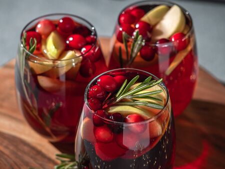 Winter sangria on tabletop. Three glasses of sangria with fruit slice, cranberry and rosemaryの写真素材