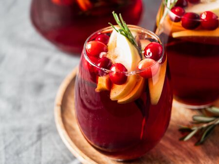 Winter sangria on tabletop with gray linen tablecloth. Glasses of sangria with fruit slice, cranberry and rosemary. Copy space for text or design. Horizontal. Top view or flat lay.の写真素材