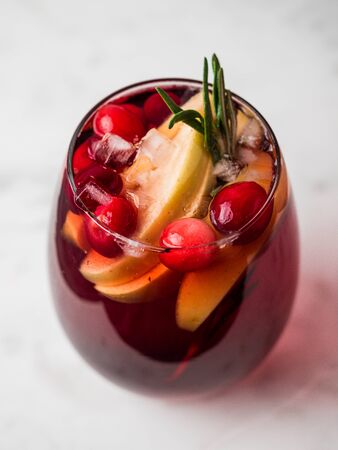 Winter sangria on tabletop with gray linen tablecloth. Glasses of sangria with fruit slice, cranberry and rosemary. Vertical.の写真素材