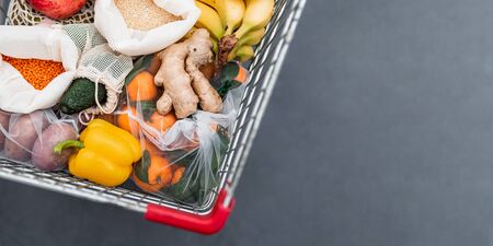 Fruit, vegetables, grains in reusable textile fabric bags in shopping cart. Top view or flat lay....