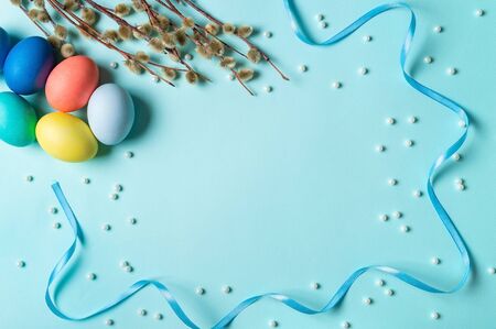 Orthodox Easter concept. Colorful eggs and pussy willow branches on blue background with empty...