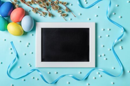 Orthodox Easter concept. Colorful eggs and pussy willow branches on blue background with empty...