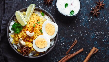 Indian Egg Biryani or anda rice top view on dark background. Egg Biryani - Basmati rice cooked with masala roasted eggs and spices, served with yogurt.の写真素材
