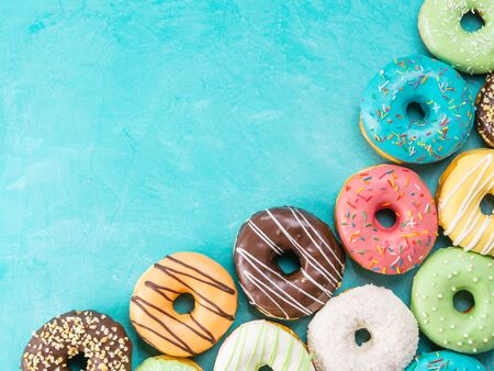 Top view of assorted donuts on blue concrete background. Colorful donuts background. Various glazed doughnuts with sprinkles.の写真素材