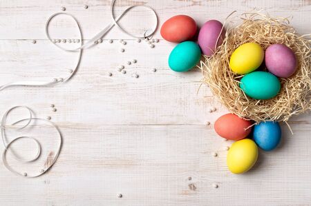 Easter concept. Colorful eggs on white wooden background with copy space for text or design. Top...