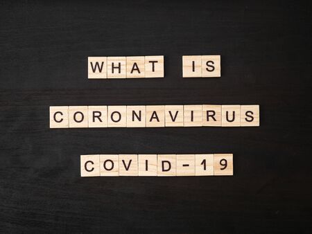 what is coronavirus COVID-19 words made of wood block. What is coronavirus COVID-19 text on dramatic atmosphere black wooden table. Coronavirus concept top view.の写真素材