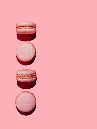Pink macarons with copy space. Row of perfect french macarons or macaroons on pink background. Top view or flat lay. Hard lightの写真素材