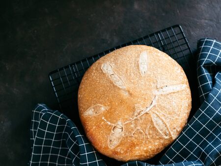 Wheat round sourdough bread. Top view of delicious homemade sourdough bread on black background with...