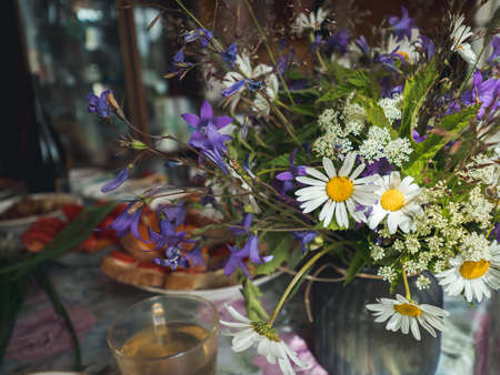 Table setting in country house with wild flowers bouqet. Field flowers bouqet with campanula and...