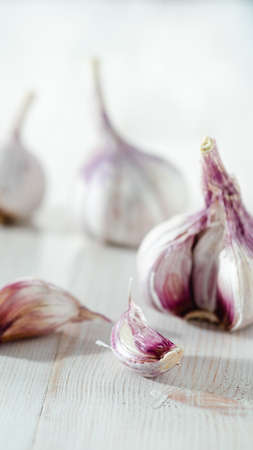 Garlic bulb with garlic cloves on white wooden background. Perfect garlic with copy space for text or design. Vertical. Shallow DOFの写真素材
