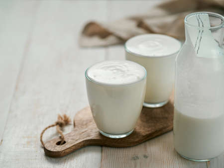 Kefir, buttermilk or yogurt with probiotics. Yogurt in glass on white wooden background. Probiotic cold fermented dairy drink. Gut health, fermented products, healthy gut flora concept. Copy spaceの写真素材