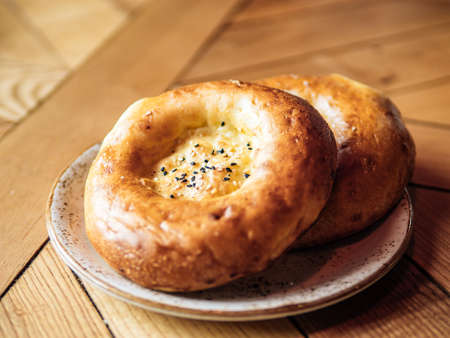 Tasty fresh tandoor bread on rustic wooden tabletop. Two tandoor flat bread cake with black sesame...