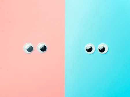 Googly eyes on blue an pink background. Top view or flat lay. Plastic toy eyes on turquoise...