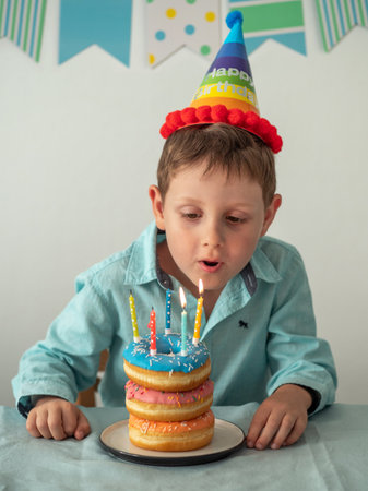 Child blows out the candle on birthday donuts cakeの写真素材