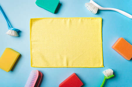 House cleaning product and empty yellow napkin in center, blue background, copy space. Flat lay or top view. Cleaning service or housekeeping concept with space for text or design in centerの写真素材