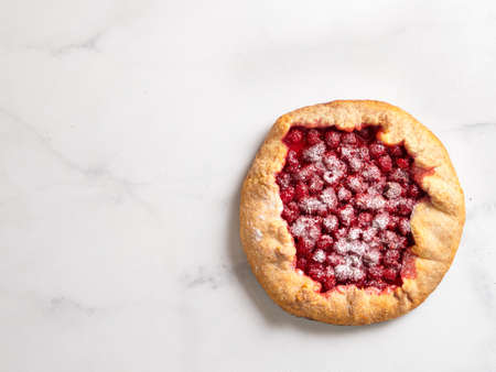 Perfect raspberry galette. Delicious rustic homemade tart with frozen or fresh raspberries on white marble background. Beautiful round shape galette with raspberries,copy space. Top view or flat layの写真素材