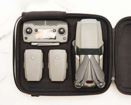 Folding drone quadcopter with full set in case. Top view or flat lay. Kit of drone UAV and accessories - controller and two battary in case over white marble backgroundの写真素材