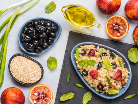 Salad with quinoa, red orange, black olives, green onion, mint and olive oil on gray concrete backkground. Vegan food. Top view or flat lay.の写真素材