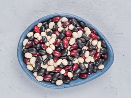 Close up view of raw mixed beans in blue plate on gray concrete background. Mixed of black, red and white beans with copy space.の写真素材