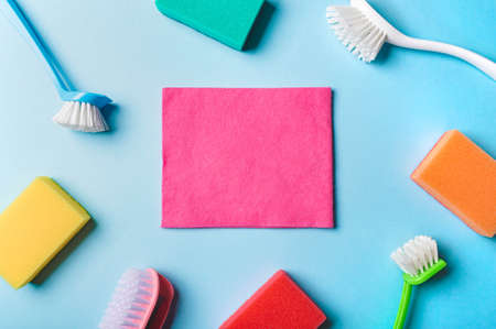 House cleaning product and empty pink napkin in center, blue background, copy space. Flat lay or top view. Cleaning service or housekeeping concept with space for text or design in centerの写真素材