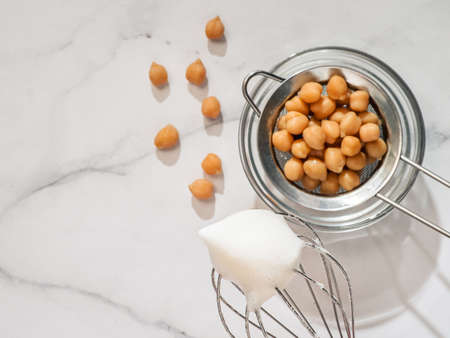 Whipped aquafaba on planetary mixer whisk, vertical. Chickpea water brine aquafaba whipped. Egg replacement in coocking. Vegan concept. Top view or flat lay. Copy spaceの写真素材