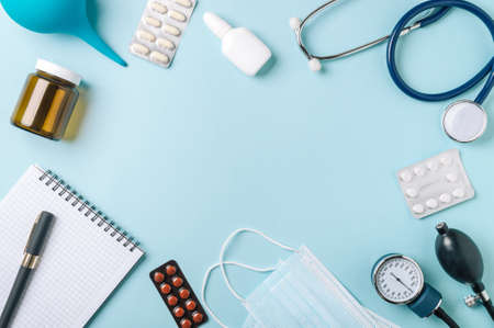 Medical concept, flat lay on blue background. Copy space in center. Stethoscope, tonometr, pills and other medical equipment on blue, top viewの写真素材
