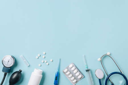 Medical concept, flat lay on blue background. Copy space. Stethoscope, tonometr, thermometer, pills and other medical equipment on blue, top viewの写真素材