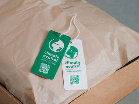 Carbon neutral product in craft corrugated box with label Climate neutral. Carbon neutral label concept in apparel, fashion, logistics indusrty and ethical consumption. Increasing awareness for customers about carbon footpintの写真素材