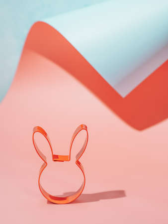 Easter bunny cookie cutter on pink and blue paper pastel background with shadows. Happy Easter Day concept. Minimal Easter concept. Copy space for text. Easter cooking baking background.の写真素材
