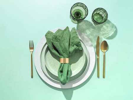 Beautiful festive table setting in green colors for St.Patricks day with golden cutlery. Top view of Saint Patricks day holiday table with green napkin and green glasses. Copy spaceの写真素材