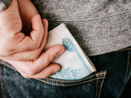 his hand put russian rubles in jeans pocket or take out from pocketの写真素材