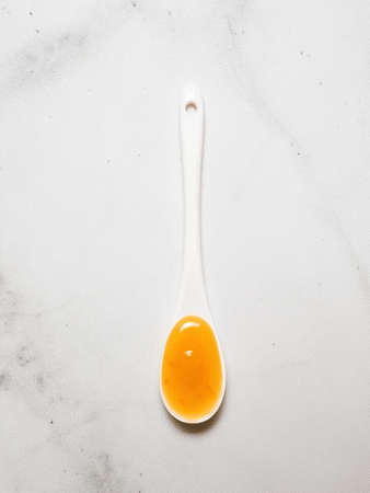 White spoon full citrus lemon curd sauce. Delicious homemade lemon or orange curd on white marble background. Vertical. Top view or flat lay. Copy spaceの写真素材