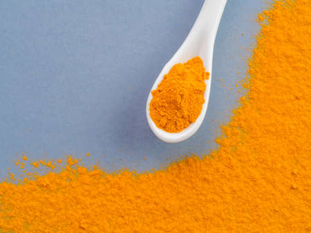 Turmeric Powder or Curcuma longa and white spoon with turmeric powder on gray background. Top view. Copy space for text.の写真素材