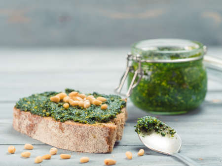Close up view of whole grain rye bread with fresh basil pesto sauce on gray wooden table. Copy space.の写真素材