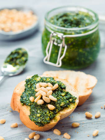 Close up view of baguette bread with fresh basil pesto sauce on gray wooden table. Copy space.の写真素材
