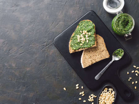 whole grain rye bread with fresh basil pesto sauce on black wooden cutting board over dark concrete background. Top view or flat-lay. Copy space.の写真素材