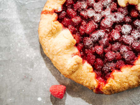 Perfect raspberry galette. Delicious rustic homemade tart with frozen or fresh raspberries on gray textured background. Beautiful round shape galette with raspberries,copy space. Top view or flat layの写真素材