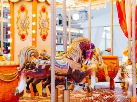 Christmas tree on french illuminated carousel background. Blurred big carousel merry go round in winter. Blurred christmas background in orange colorsの写真素材