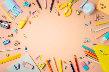 Creative student desk with school supplies and copy space in center. Top view or flat lay. Trendy back to school flat lay on peach pink backgroundの写真素材