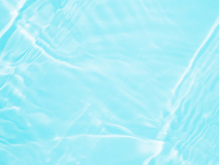 Ripple water texture on blue pool background. Shadow of water on sunlight. Mockup for product, spa or travel background. Marble blue water surface as wallpaper backgroundの写真素材