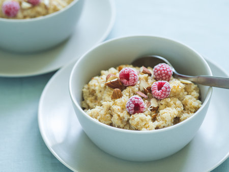 Quinoa porrige on tabletop. Two bowl wit quinoa milk porridge with berries and almond. Frozen raspberries in quinoa porrigeの写真素材