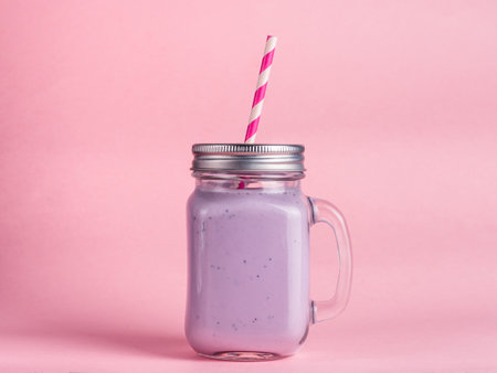 Blueberry smoothie in mason jar glass on pink backgroundの写真素材