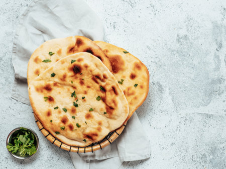 Fresh naan bread on gray cement background with copy space. Top view of several perfect naan...