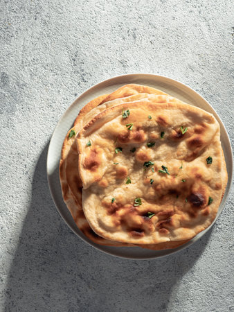 Fresh naan bread on gray cement background with copy space. Top view of several perfect naan flatbreads. Verticalの写真素材